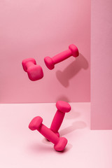 Wall Mural - pink bright dumbbells flying in air on pink background