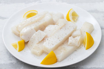 Wall Mural - raw squid with pepper and fresh lemon on white plate