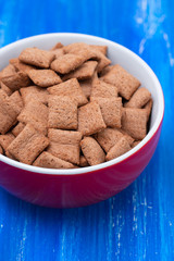 Sticker - Chocolate pillows in red bowl on blue wooden background