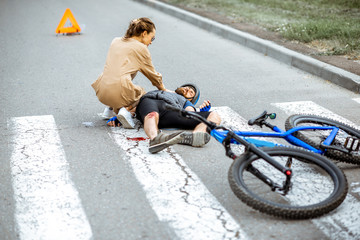 Wall Mural - Road accident with injured cyclist lying on the pedestrian crossing near the broken bicycle, worried woman driver calling and checking men's pulse