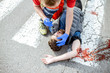 © rh2010 - Medic checking unconscious person with flashlight, applying first aid to the bleeding person on the road after the accident on the pedestrian crossing