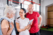 © leszekglasner - Personal trainer showing results of training on tablet to senior couple