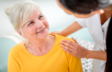 Nurse during home visit talking with senior female and giving treatment advices