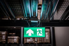 Green Emergency Exit Sign Or Fire Exit Sign Showing The Way To Escape With Arrow Symbol.