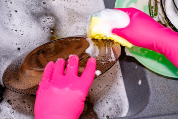 Wall Mural - The process of washing plates in the sink, hands and plates closeup. Detergent foams. Cleaning.