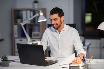 Sticker - business, deadline and people concept - businessman with laptop computer and papers working at night office