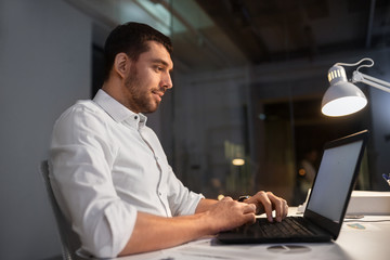 Wall Mural - business, deadline and people concept - businessman with laptop computer working at night office