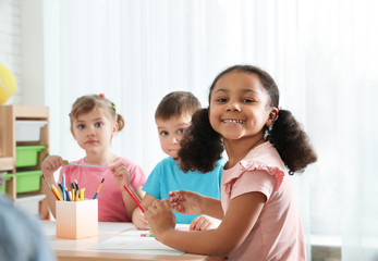 Poster - Cute children drawing together at table indoors. Kindergarten playtime activities