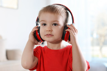 Cute child listening to music with headphones indoors