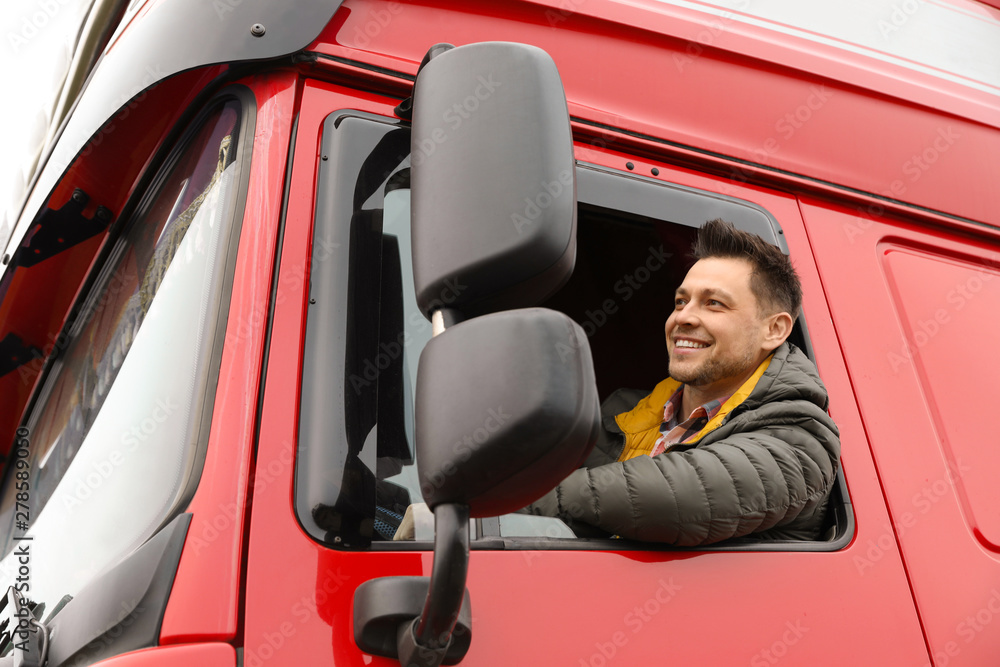 Portrait of happy driver in cab of modern truck - obrazy, fototapety, plakaty 