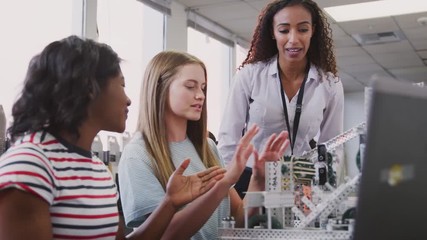 Wall Mural - Teacher With Two Female College Students Building Machine In Science Robotics Or Engineering Class