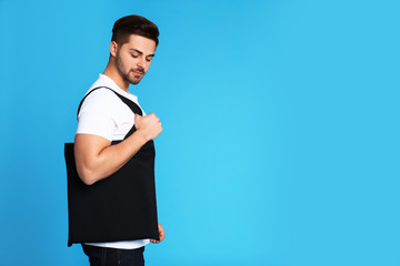 Canvas Print - Portrait of young man with eco bag on blue background. Space for text