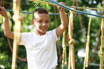 Poster - Little African-American boy climbing in adventure park. Summer camp