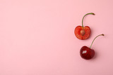 Cut and whole sweet cherries on pink background, top view. Space for text