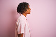 Afro american man with dreadlocks wearing elegant shirt standing over isolated pink background looking to side, relax profile pose with natural face with confident smile.