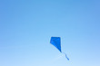 A blue kite soars in a cloudless sky. The concept of freedom, summer hobbies, entertainment in nature. Minimalism, space for text, shades of blue.