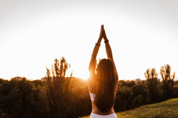 young beautiful asian woman doing yoga in a park at sunset. Yoga and healthy lifestyle concept