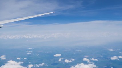 Wall Mural - Airplane flight. Wing of an airplane flying above the clouds with sunset sky. View from the window of the plane. Aircraft. Traveling by air.