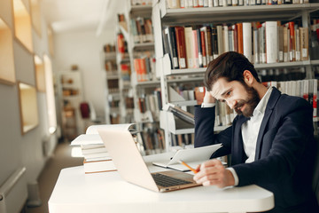 Wall Mural - Man in a library. Guy in a black suit. Student with a books.