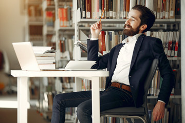 Wall Mural - Man in a library. Guy in a black suit. Student with a books.