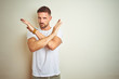 © Krakenimages.com - Young handsome man wearing casual white t-shirt over isolated background Rejection expression crossing arms doing negative sign, angry face