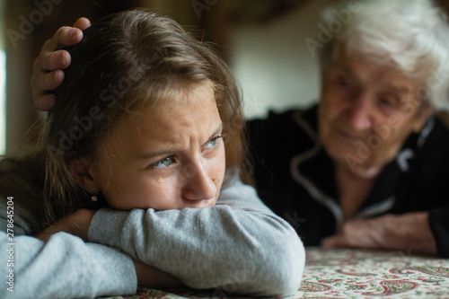 Fotomural Teen girl cries, grandmother soothes and strokes her head.