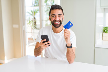 Handsome man using credit card to pay online with smartphone