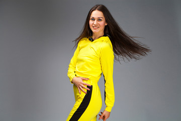 Wall Mural - Portrait of a young beautiful brunette woman in yellow tracksuit