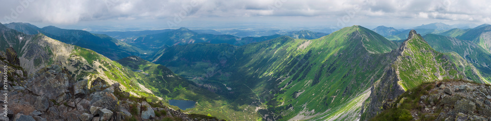 Panoramic view from Rohac peak on Western Tatra mountains or Rohace panorama. Sharp green mountains - ostry rohac, placlive and volovec with hiking trail on ridge. Summer blue sky white clouds. - obrazy, fototapety, plakaty 
