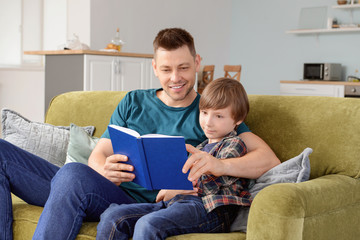 Wall Mural - Father and his little son reading book at home
