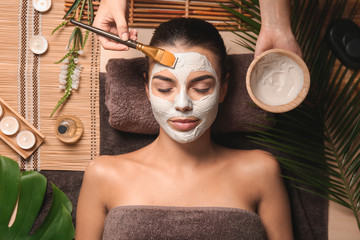 Poster - Cosmetologist applying mask on woman's face in spa salon