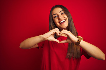 Young beautiful woman wearing t-shirt standing over isolated red background smiling in love doing heart symbol shape with hands. Romantic concept.