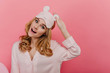 © Look! - Interested curly woman with big eyes laughing in studio. Dreamy young female model in eyemask expressing surprised emotions on bright background.