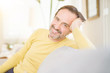 © Krakenimages.com - Handsome middle age man sitting on the sofa relaxed and smiling at the camera at home