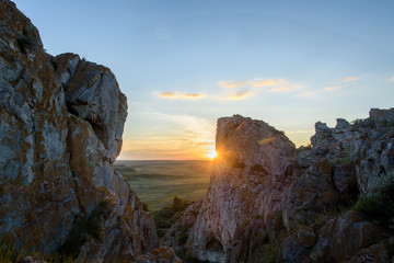 Sunset in the Kazakh steppe. Spacious steppes surrounded by low mountains. Beautiful view of horizon.