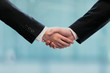 © UTS - 握手するビジネスマンとビジネスウーマンの手元