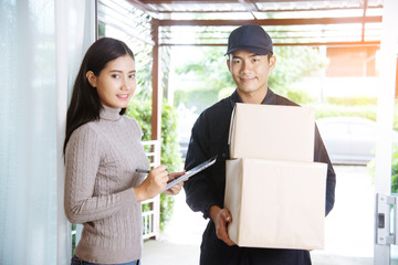 Delivery mail shipping package services . Young deliveryman in uniform shipping goods package to recipient from shopping online and signing for got parcel package service on clipboard.