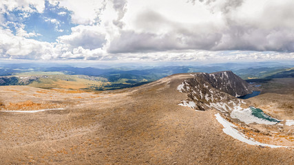 The landscape of the high point of the mountain is over two thousand kilometers above the ground level. Mountain panorama with a snow-free core, below a clear blue lake.