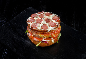 Wall Mural - Crispy burger with sausages, tomatoes sauce, flowing mozzarella, pork meat steak.