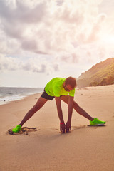 Wall Mural - Sportsman stretching on a tropical sandy beach.