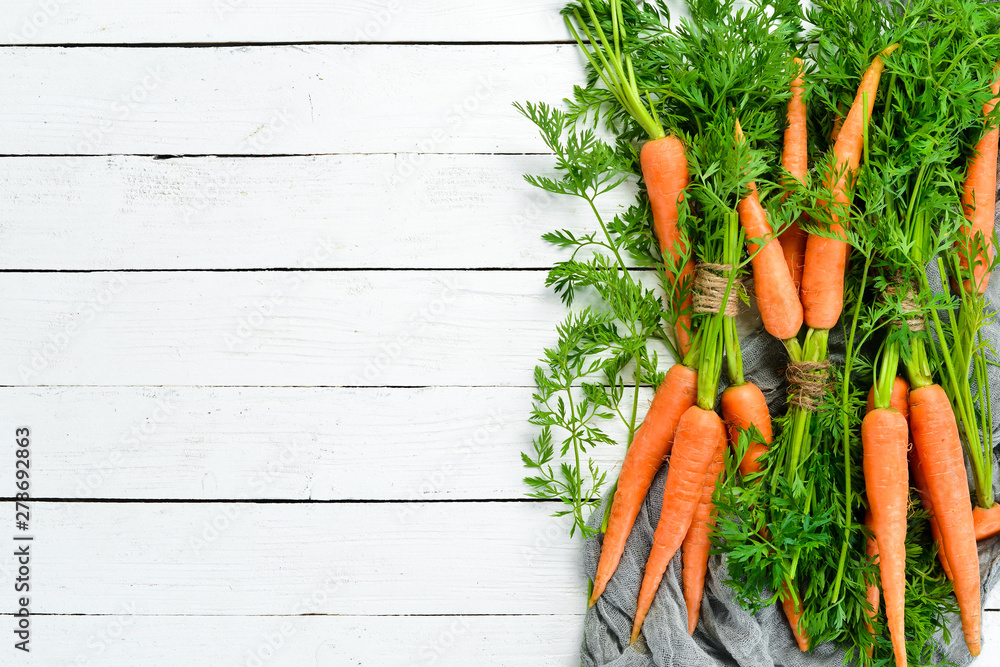 Fresh carrots on a white wooden background. Top view. Free space for your text. - obrazy, fototapety, plakaty 