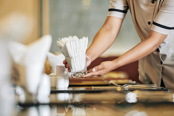 Close-up of waitress setting the table in the restaurant she putting the napkins on the table