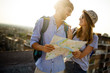 © NDABCREATIVITY - Happy couple on vacation sightseeing city with map