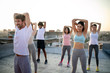 © NDABCREATIVITY - Group of fit healthy friends, people exercising together outdoor on rooftop