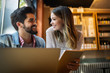 © NDABCREATIVITY - Smiling friends using notebook in cafe at the university