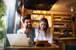 © NDABCREATIVITY - Young couple is working in cafe on laptop and smiling.