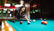 © NDABCREATIVITY - Young smiling girl playing billiard in club