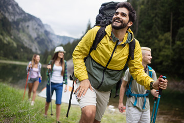 Wall Mural - smiling friends walking with backpacks. adventure, travel, tourism, hike and people concept.