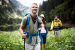 © NDABCREATIVITY - Group of smiling friends hiking with backpacks outdoors. Travel, tourism, hike and people concept.