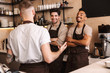© Drobot Dean - Group of cheerful men baristas wearing aprons